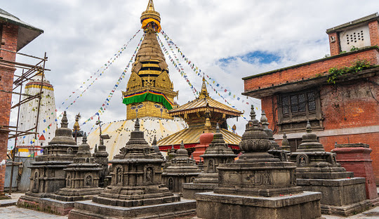 Stupa in Swayambhunath temple also called Monkey Temple, with traditional "Eyes of Buddha" painting on it and little stone stupas in foreground. Kathmandu city, travel in Nepal concept.