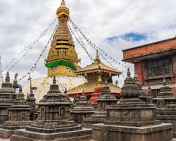 Stupa in Swayambhunath temple also called Monkey Temple, with traditional "Eyes of Buddha" painting on it and little stone stupas in foreground. Kathmandu city, travel in Nepal concept.